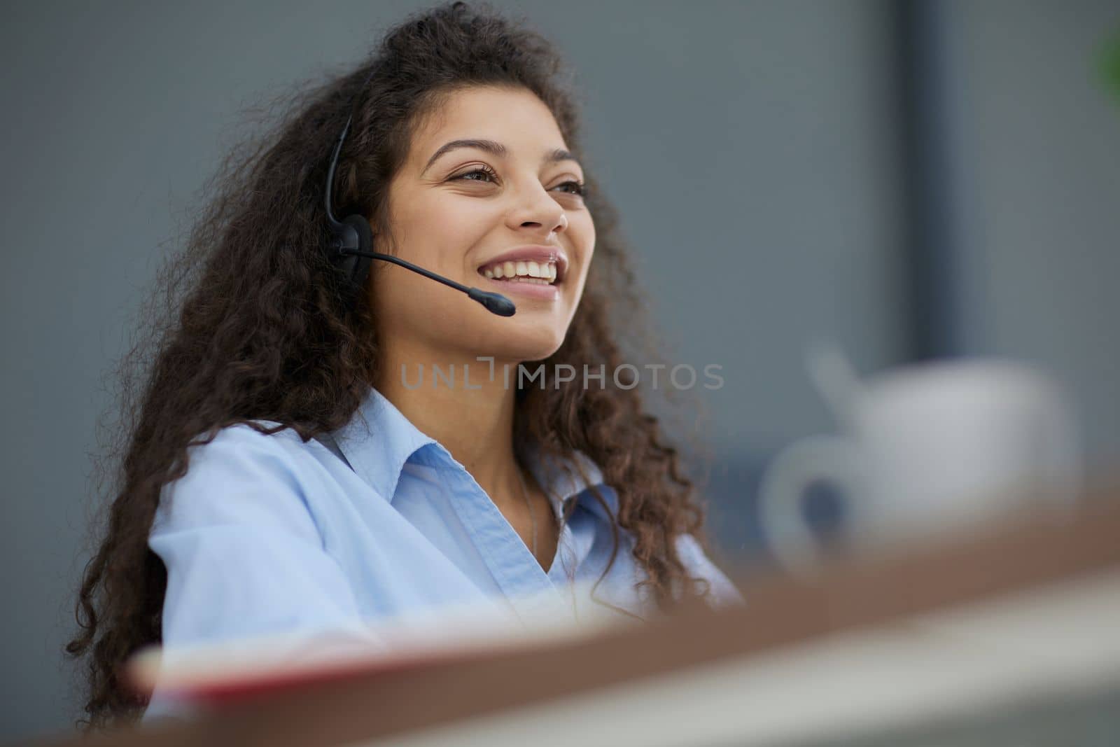 Brunette business woman using headset to communicate and advise people in customer service office. Call centre.