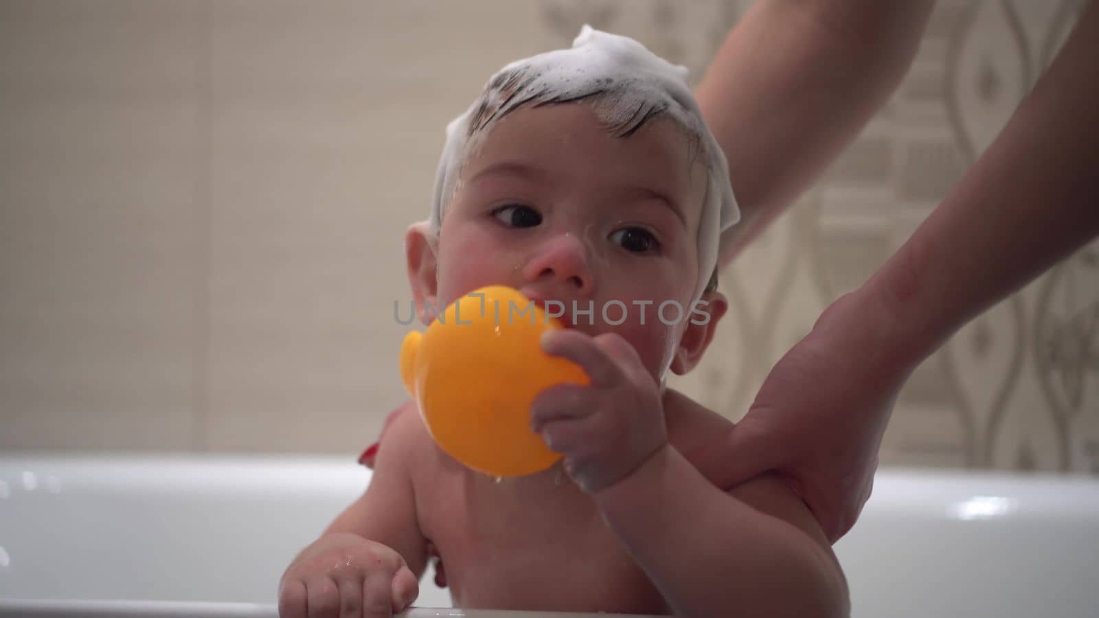 Close-up of a child's face in the bathroom. A little boy in the bathroom bathes with foam on his head. 4k