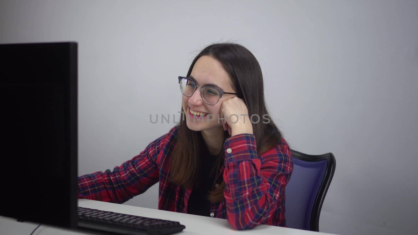 The female IT specialist looks at the monitor and laughs. A woman in the office at work is watching a series and laughing. 4k