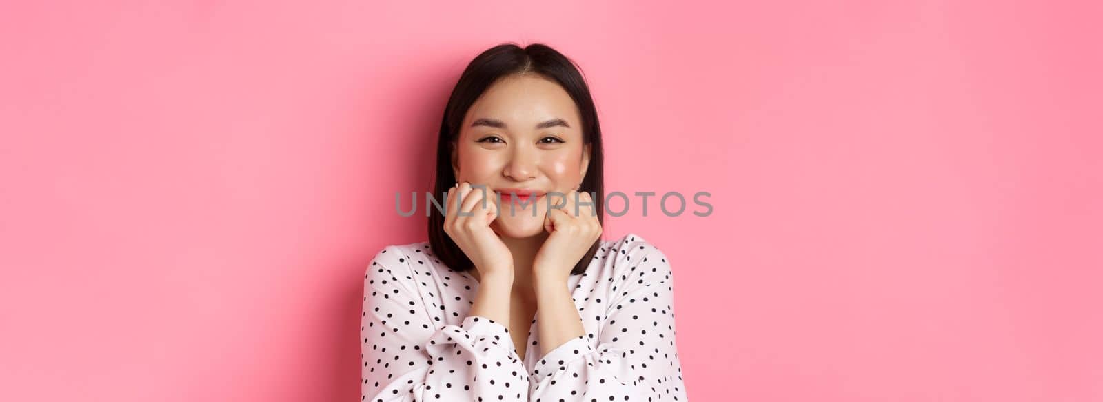 Beauty and lifestyle concept. Close-up of adorable asian woman showing puffy cheeks, smiling and looking happy, standing over pink background by Benzoix