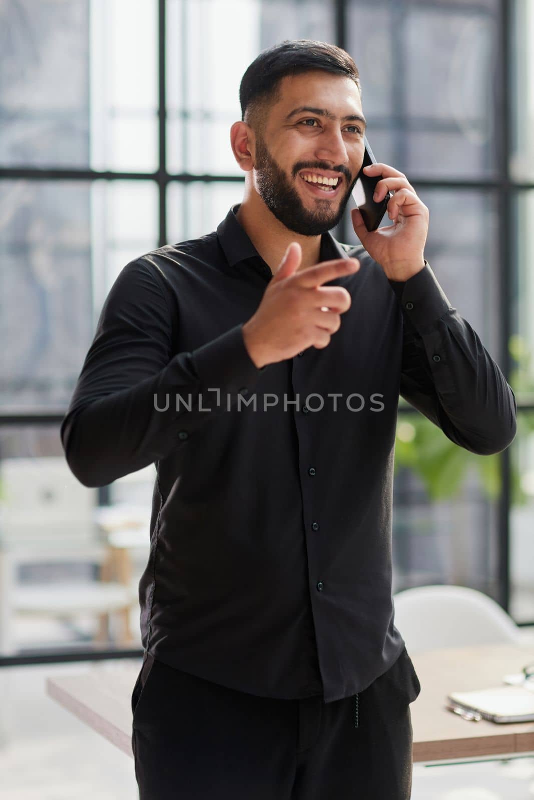 young man in a black shirt talking on the phone in the office