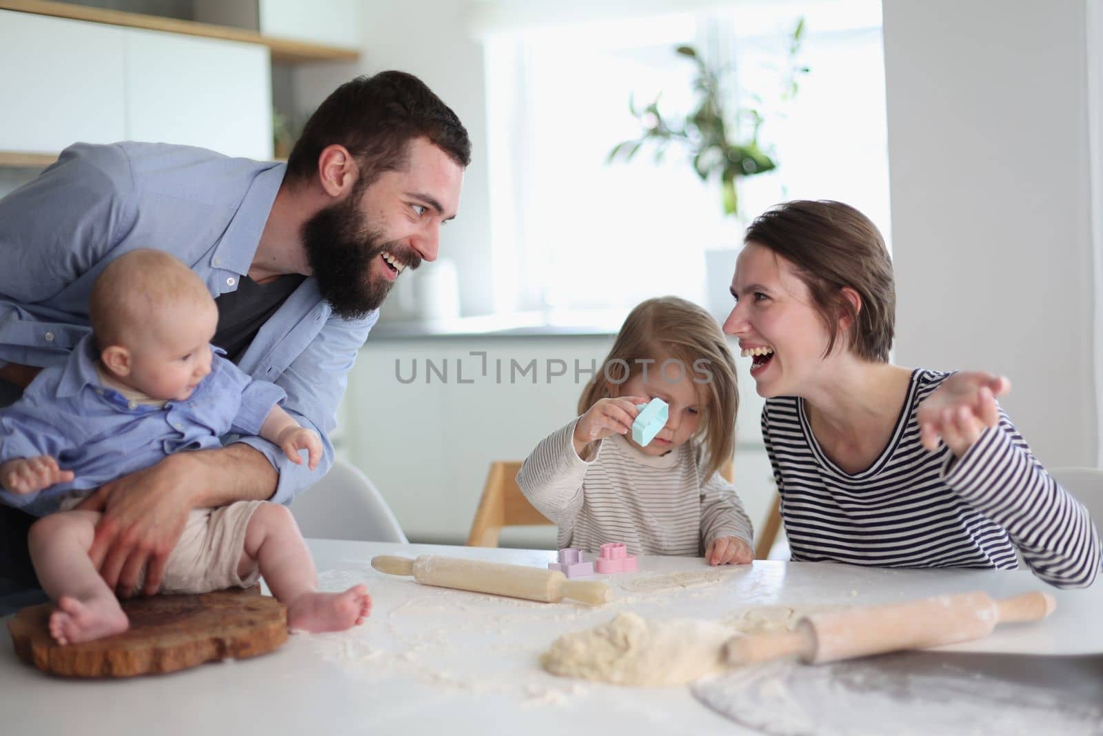 Happy parents playing with their children in the kitchen