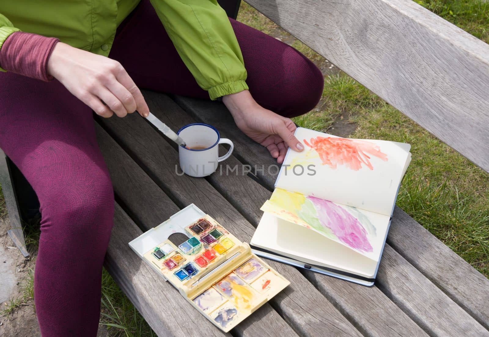 a woman draws a sketch with watercolors in a notebook in the open air and drinks tea at a picnic, High quality photo