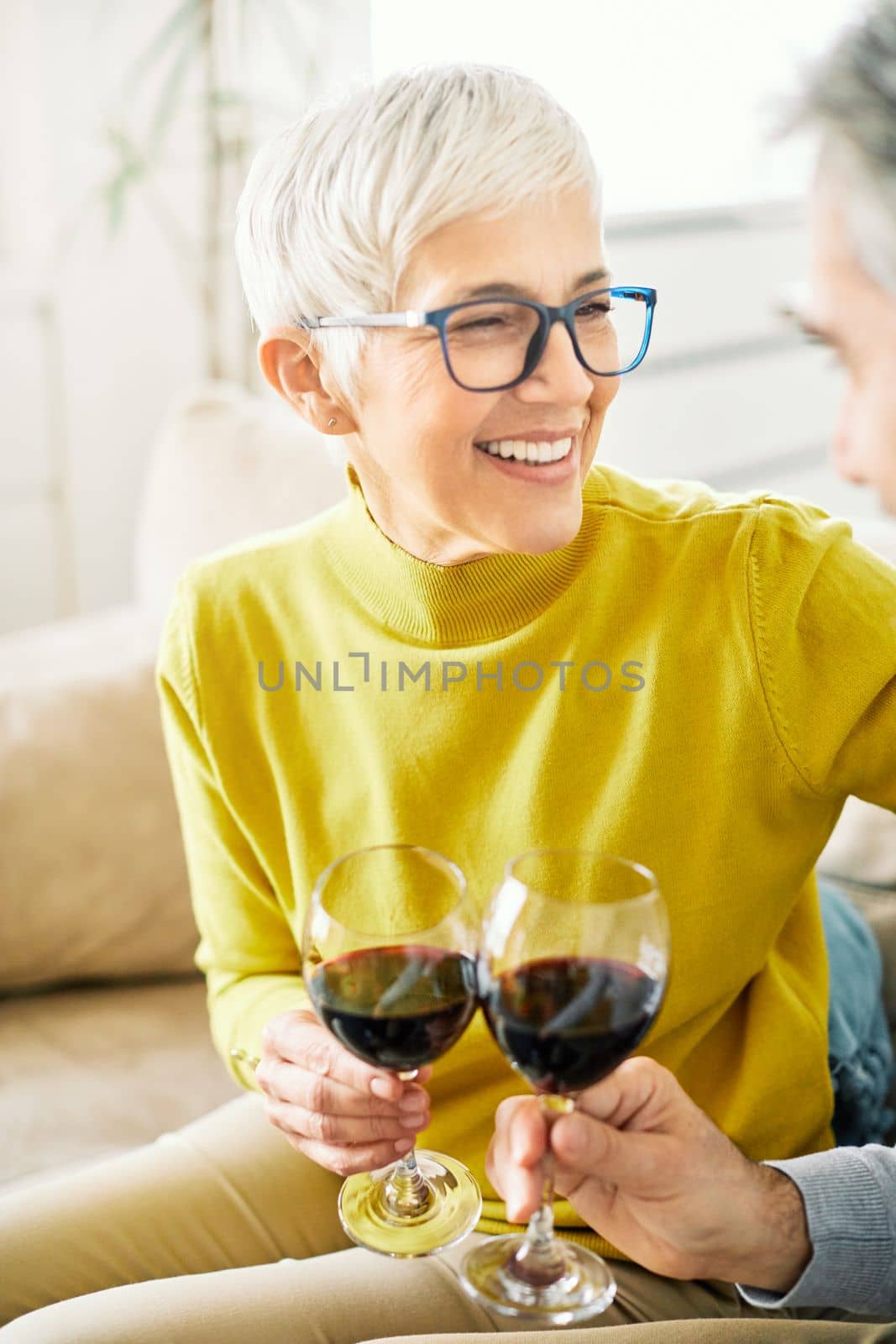 Portrait of a senior woman drinking wine while sitting on the sofa at home
