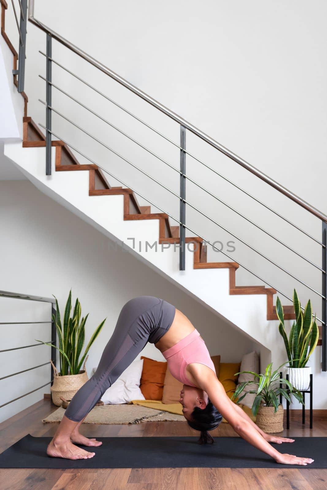 Young asian woman doing downward facing dog at home living room. Vertical image. Copy space. Healthy lifestyle.