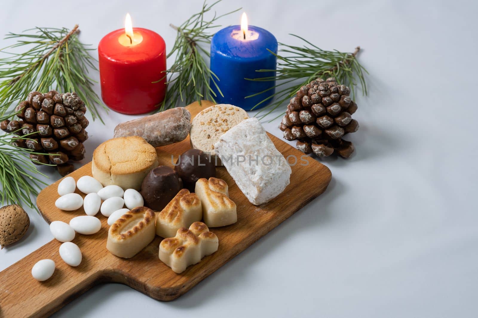 typical christmas sweets on the table decorated with pine cones, pine branches and coloured candles.