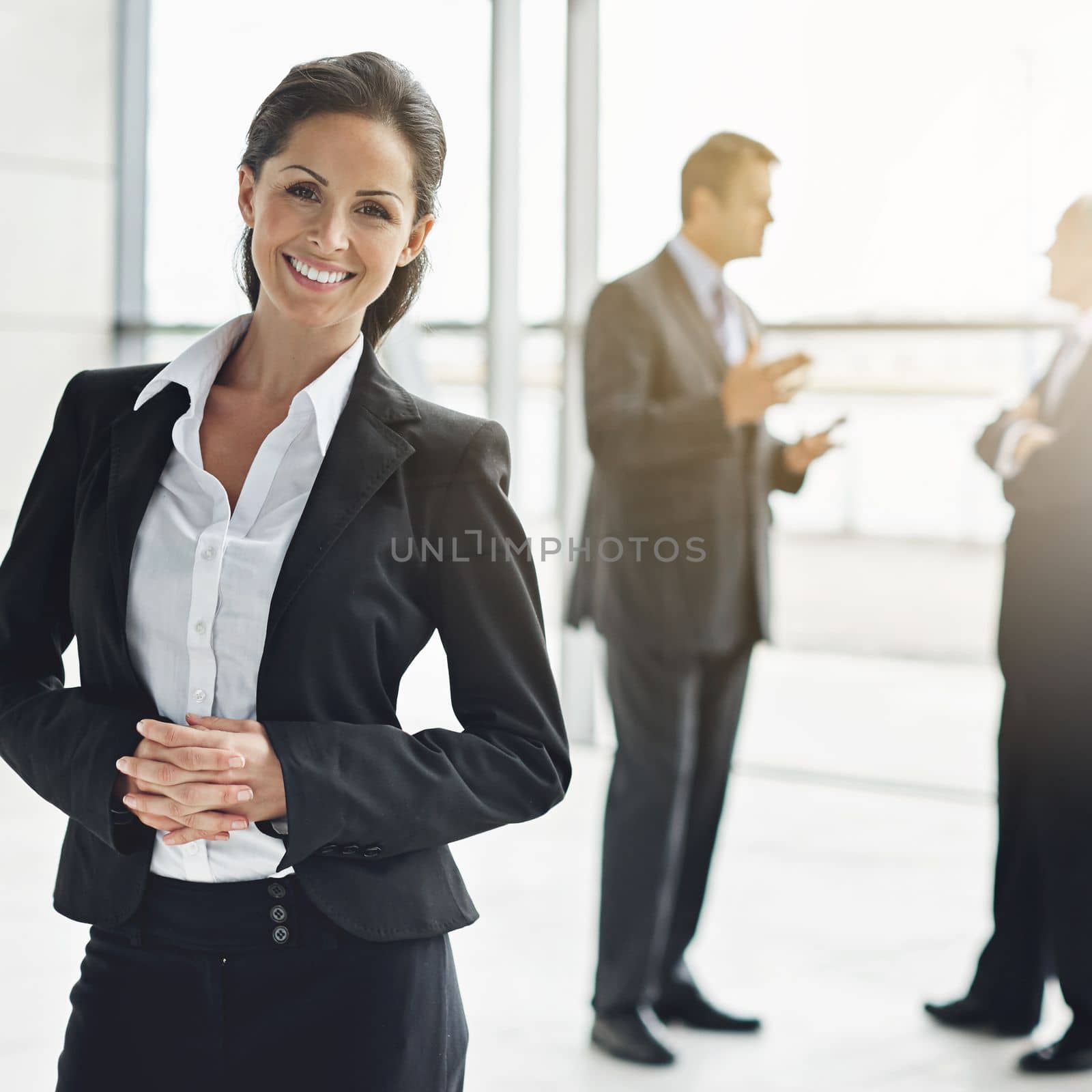 Shes the consumate professional. Cropped portrait of a businesswoman standing a lobby with her colleagues in the background