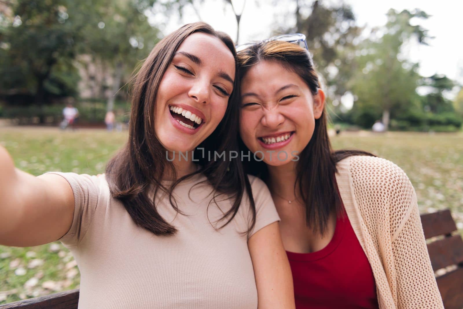 selfie photo of two happy young women laughing at park, concept of youth and friendship