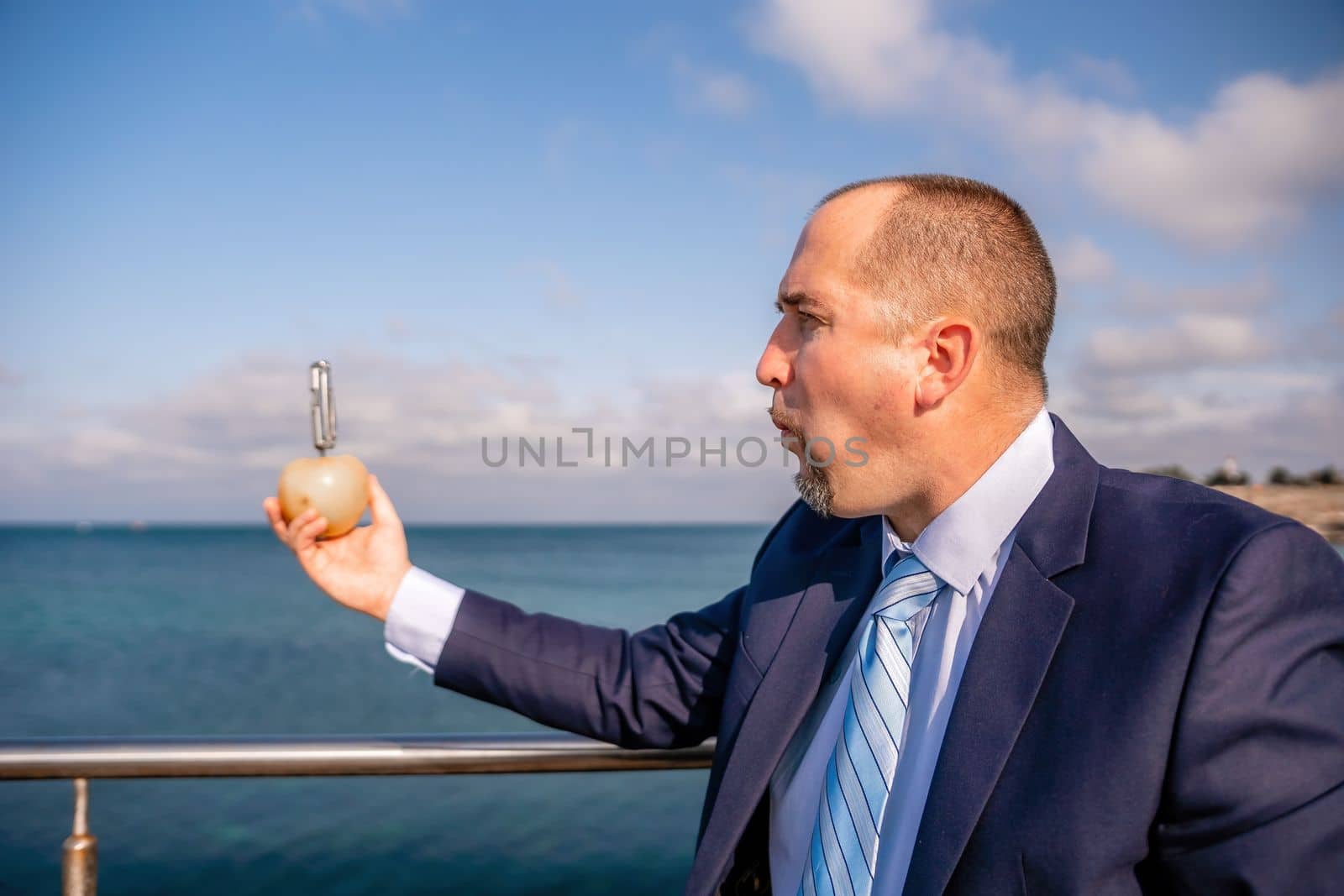 Man apple park. Hipster millennial man in a tie and jacket takes a bite out of an apple while sitting on a park bench in slow motion Young business people eating golden apples in lunch time. by panophotograph