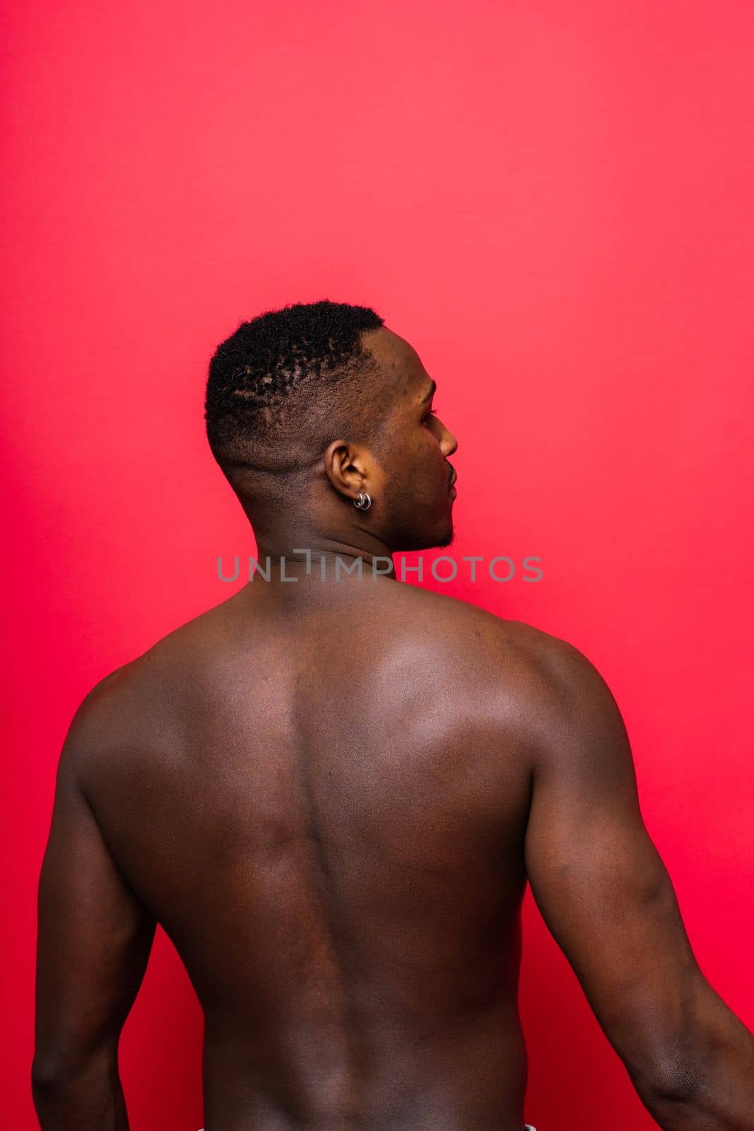 Young handsome african man topless portrait in studio on red background