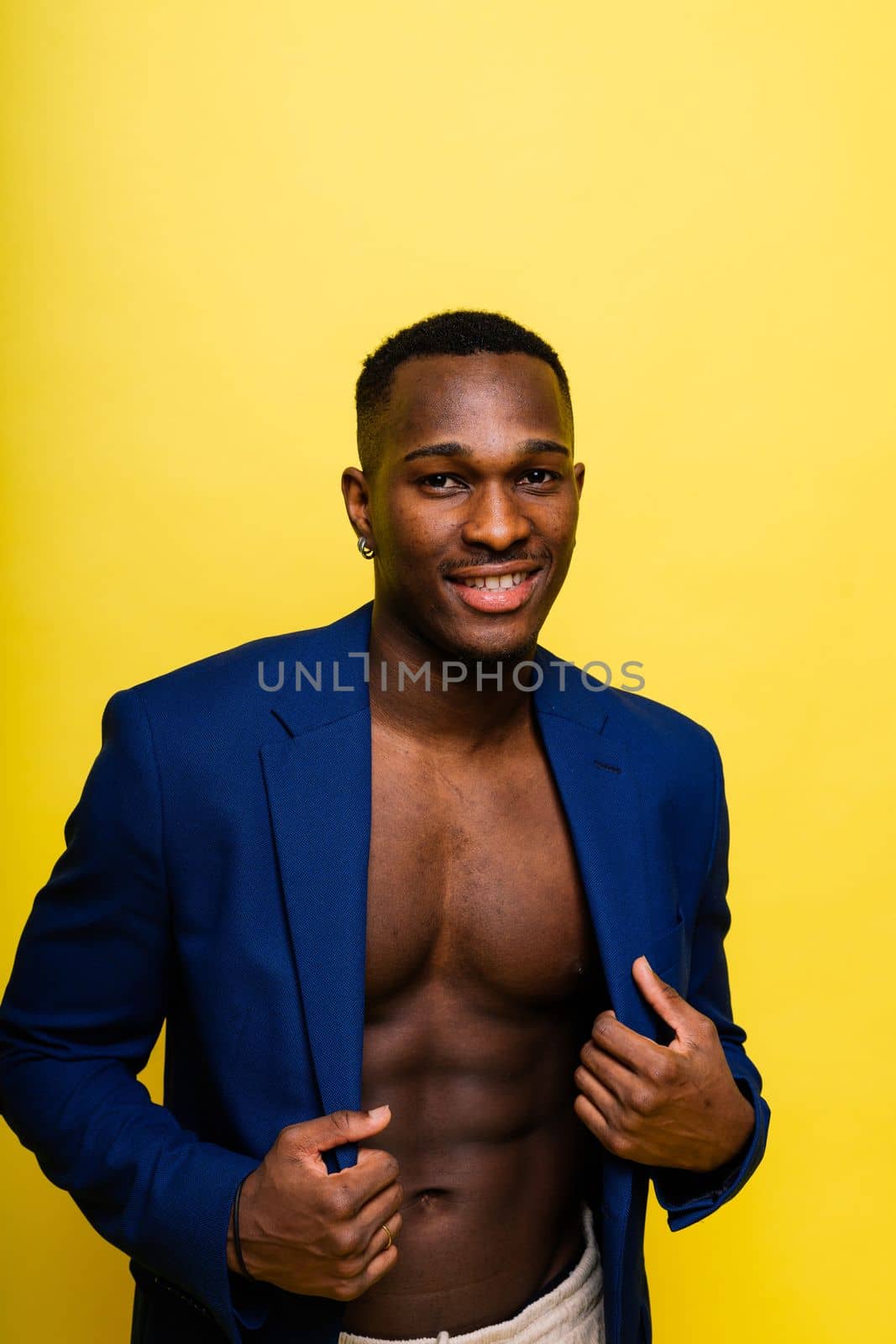 Guy in blue suit on yellow background. Handsome athletic man in jacket smiling by Zelenin