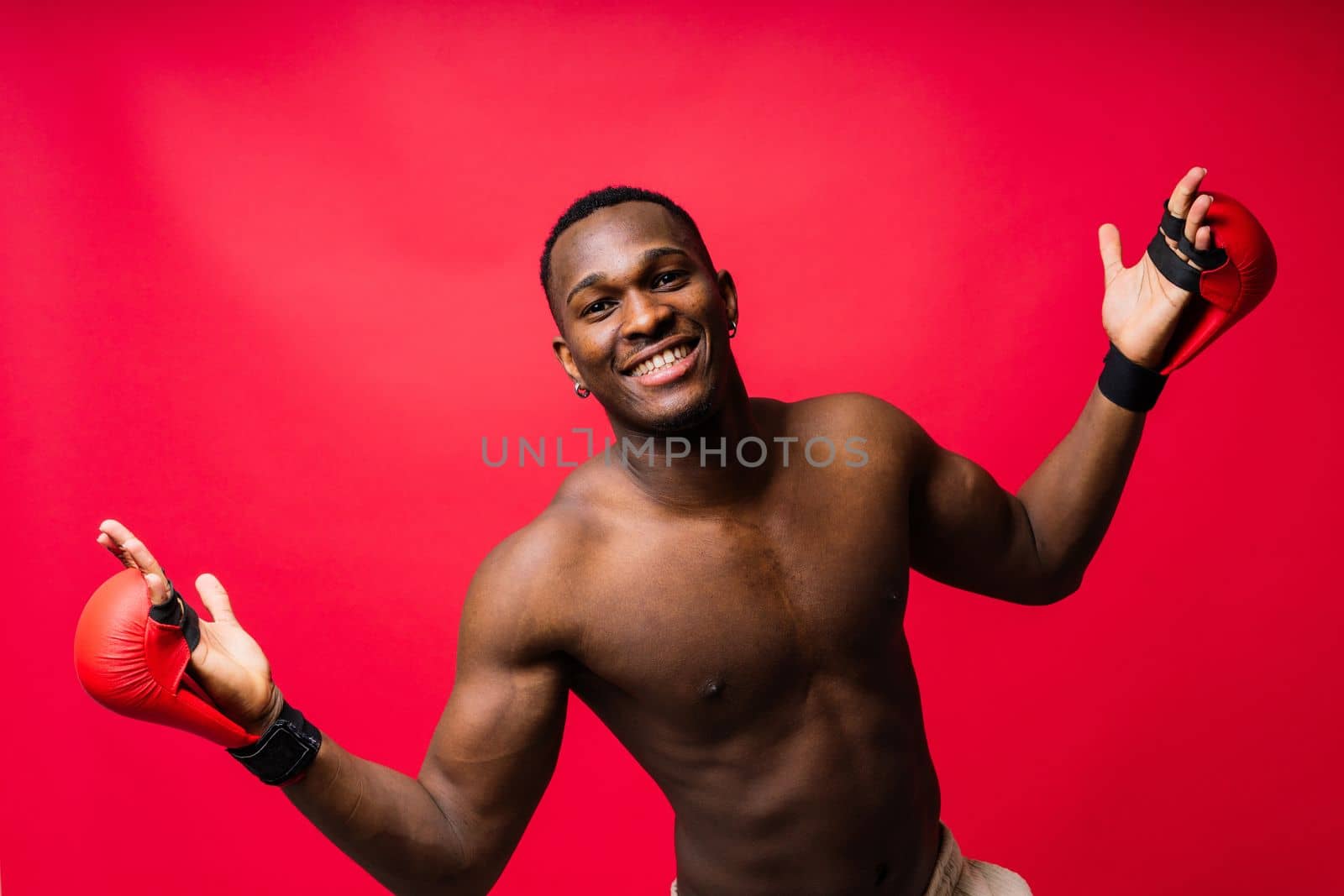 Muscular serious looking african boxer training, in studio red background