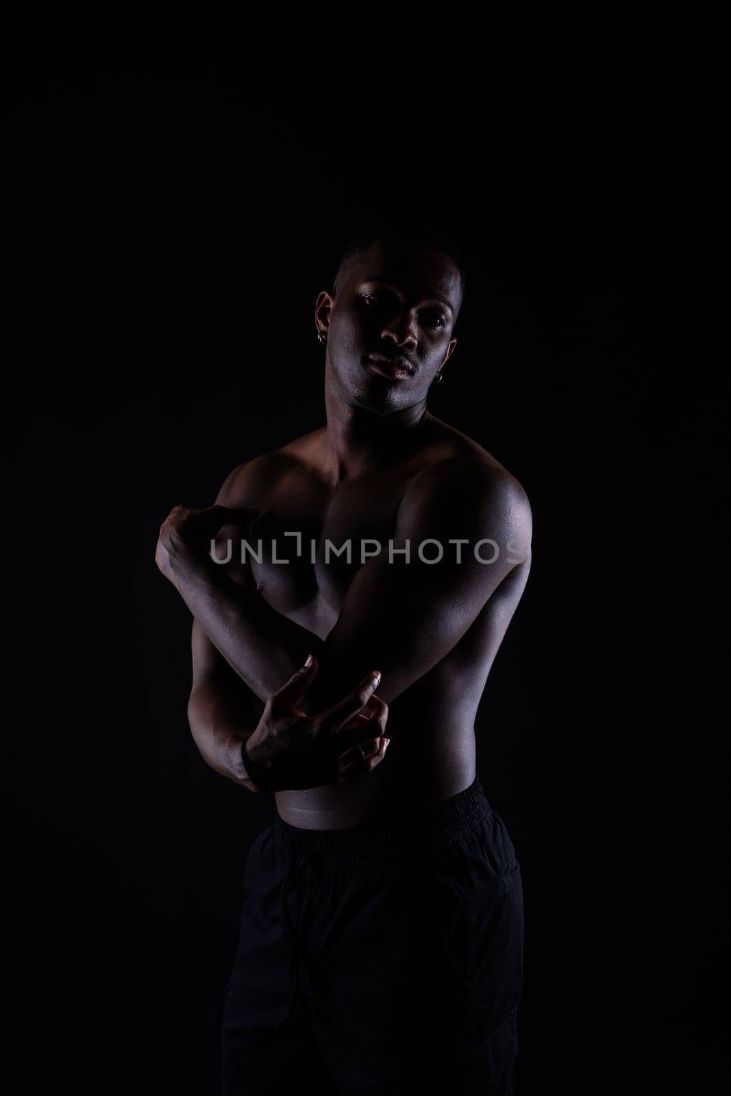Portrait of athletic african american man topless, black background