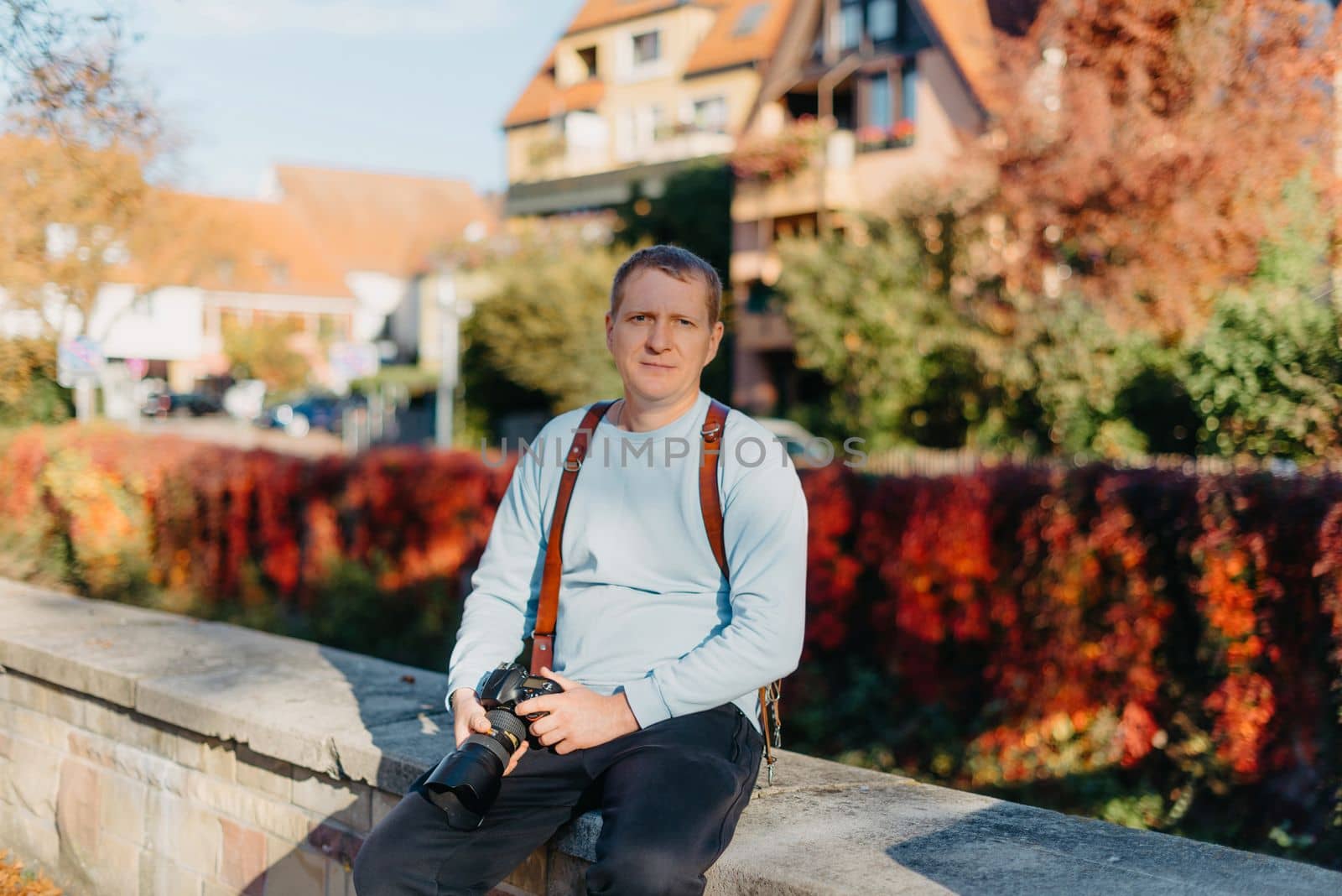 Man Sitting on Stairs in Old European City And Holding Photo Camera. Contemporary Stylish Blogger And Photographer