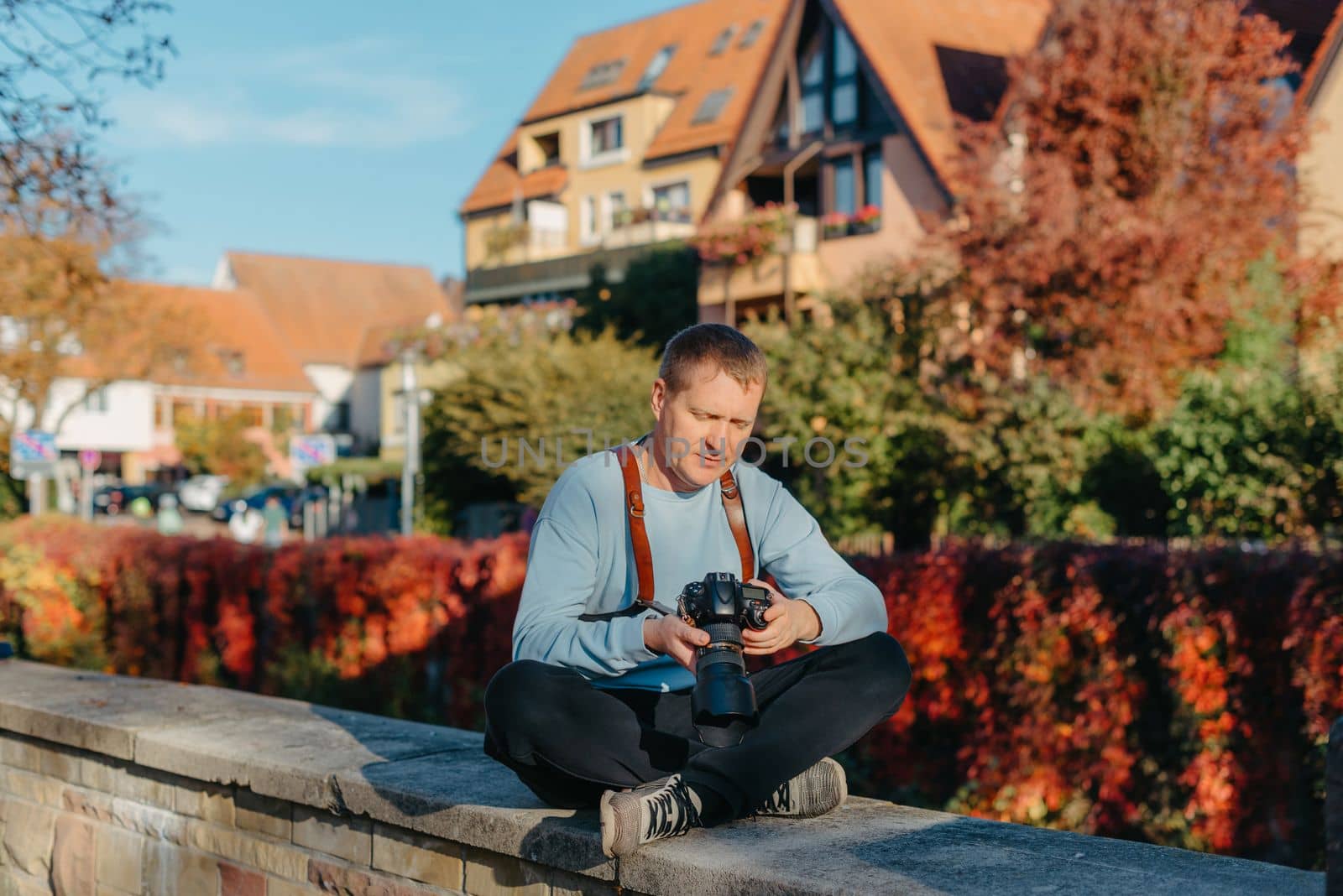 Man Sitting on Stairs in Old European City And Holding Photo Camera. Contemporary Stylish Blogger And Photographer