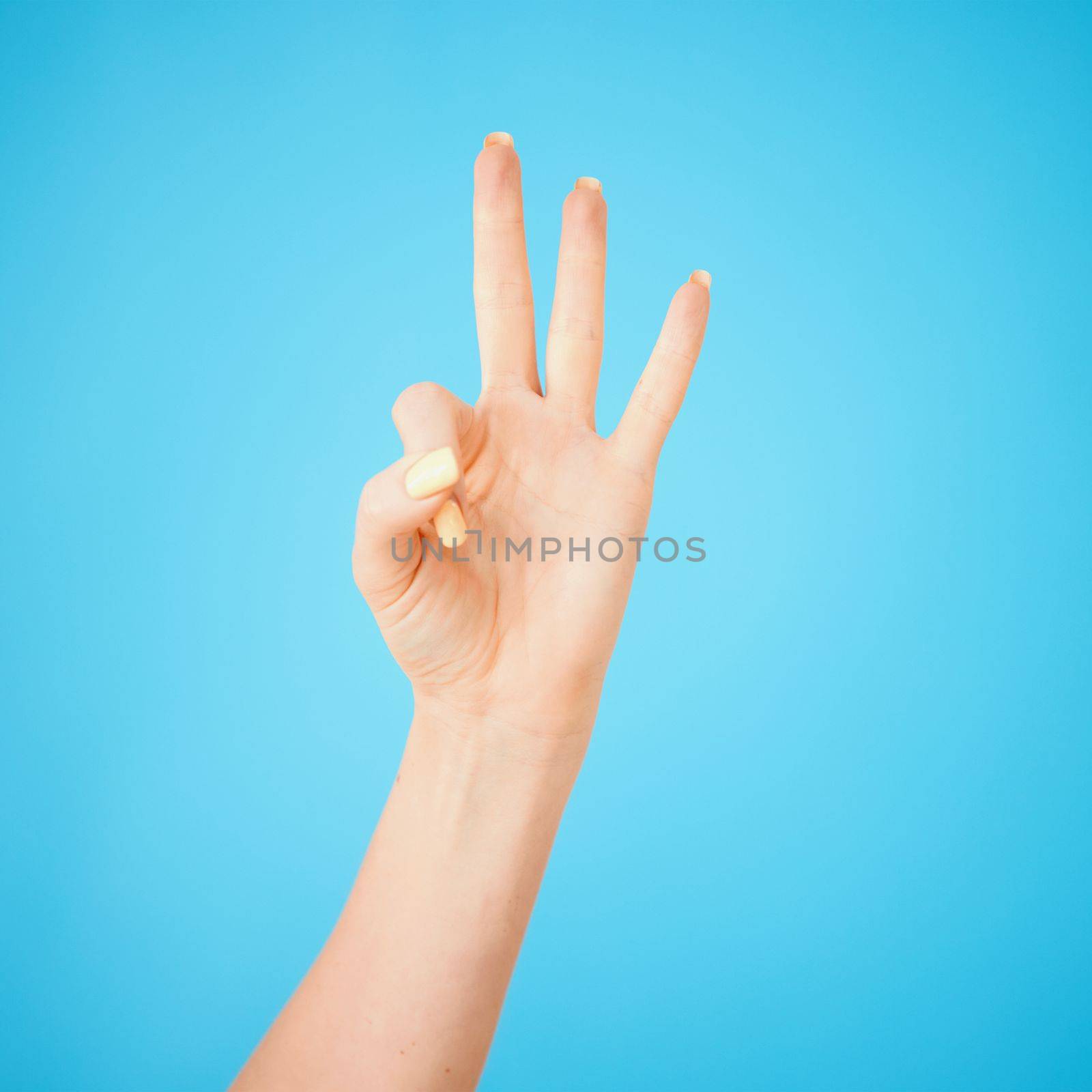 Not all communication is verbal. Studio shot of an unrecognisable woman showing three fingers against a blue background