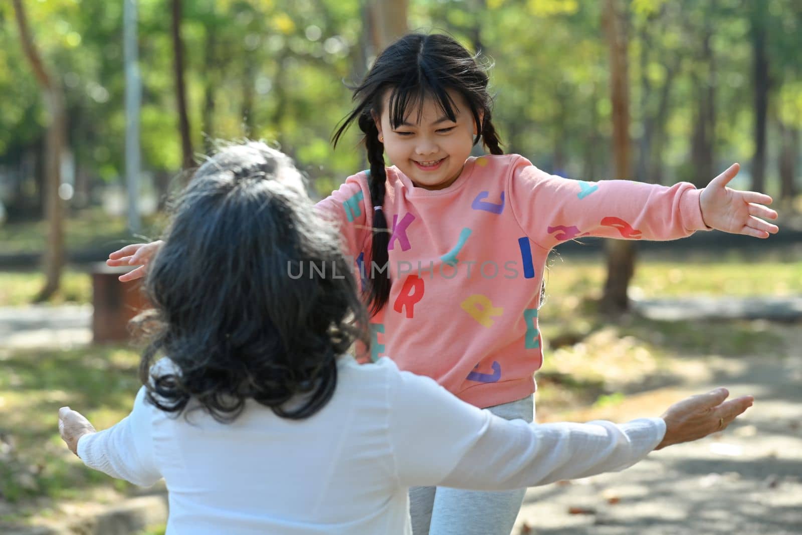 Shot of little girl running to hug grandmother with arms open. Happy moment, family and love concept by prathanchorruangsak