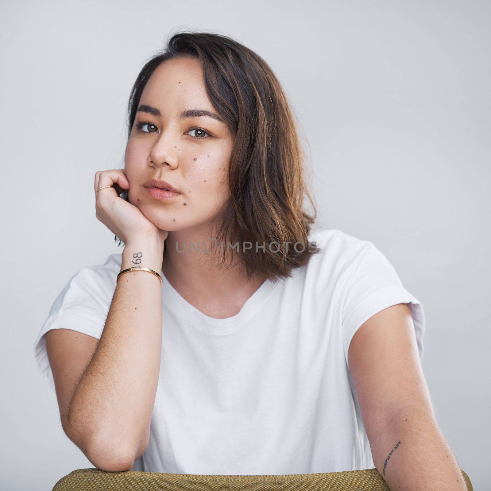 Beauty begins the moment you decide to be yourself. a beautiful young woman sitting against a white background