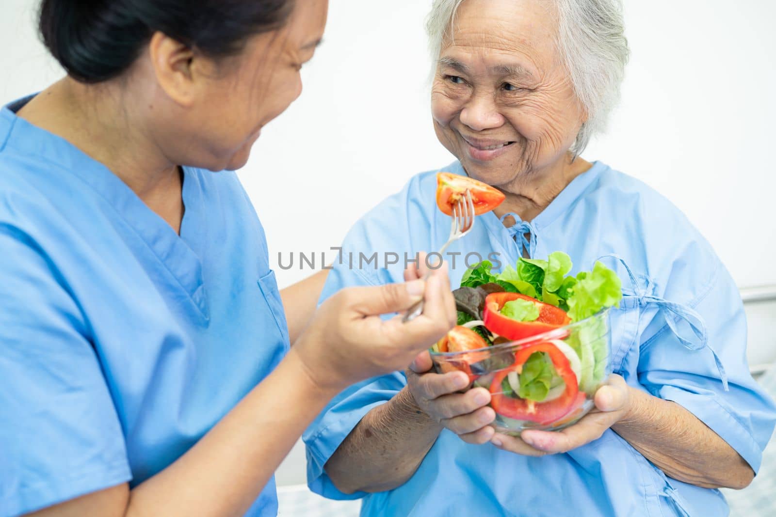Asian senior or elderly old lady woman patient eating breakfast vegetable healthy food with hope and happy while sitting and hungry on bed in hospital. by pamai