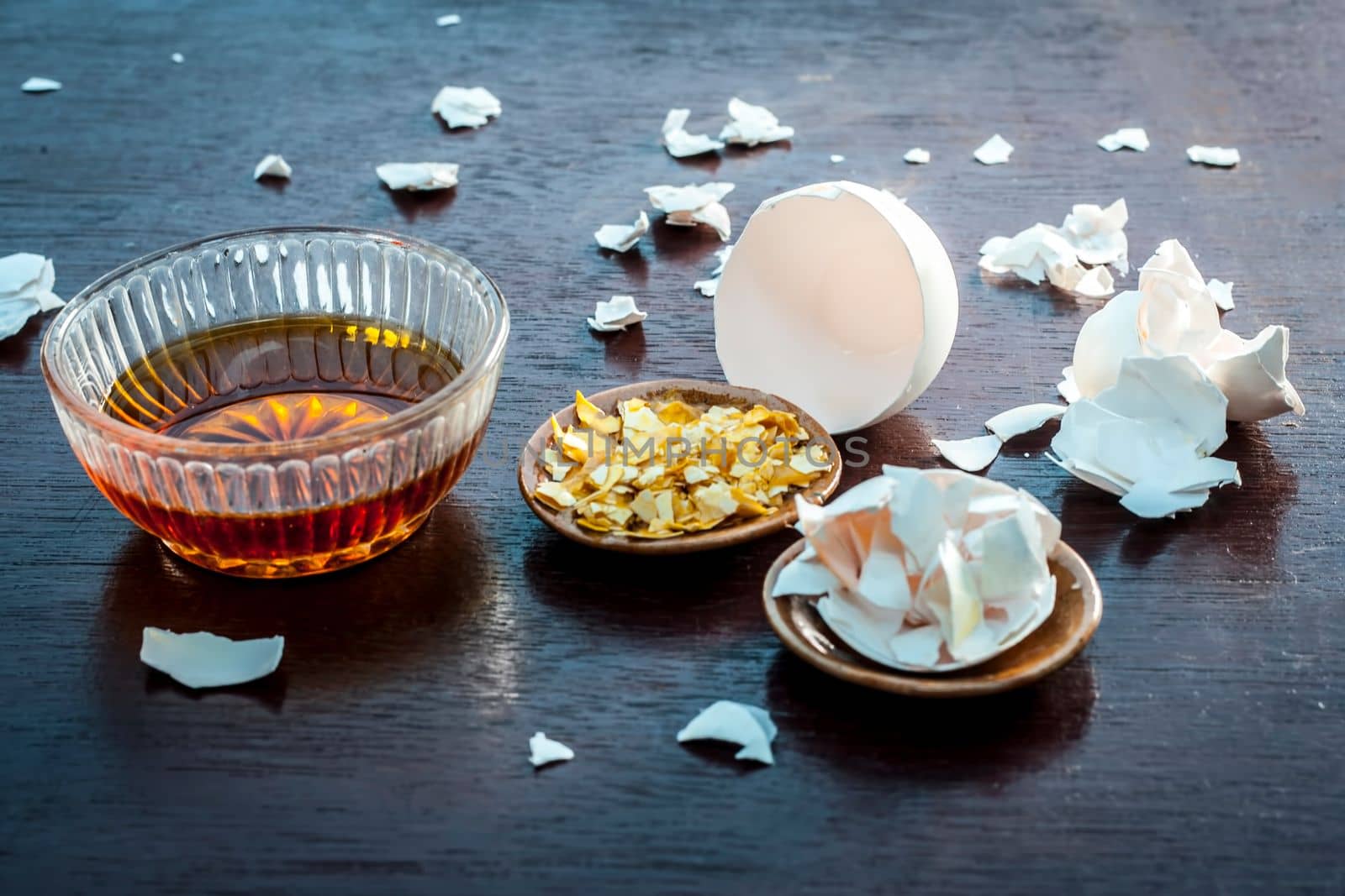 Close up of face pack consisting of egg peel and honey on a wooden surface in dark Gothic colors for soft and smoother skin.