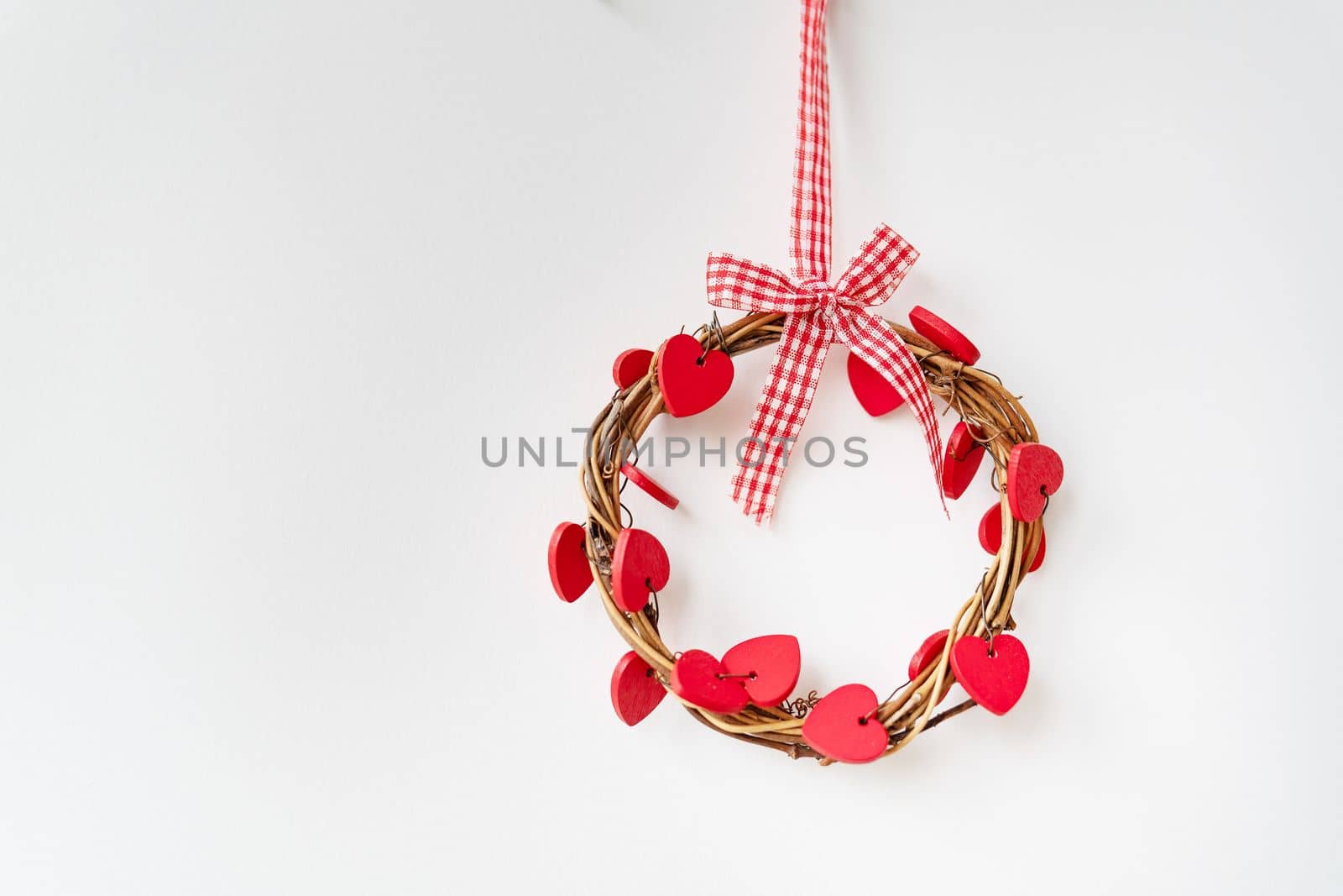 A decorative ring with wooden red hearts hangs on the wall. The concept of holiday, love, St. Valentine's Day. by sfinks