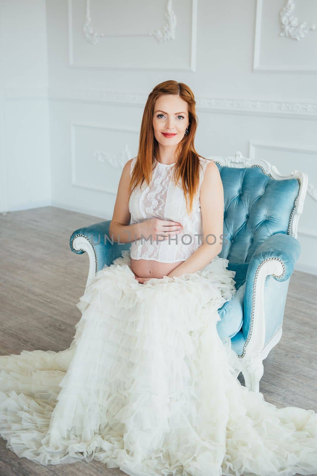 red-haired pregnant young girl in a blue armchair by Andreua