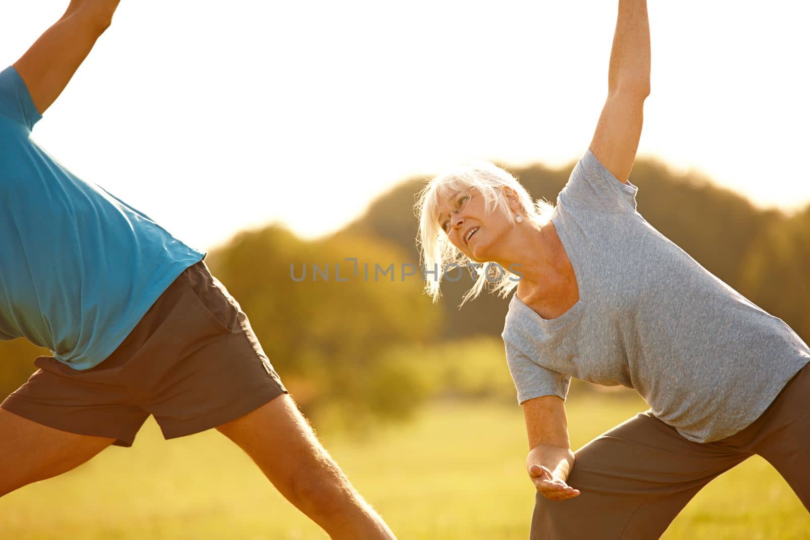 Stretching further each day. a mature couple doing yoga together outdoors
