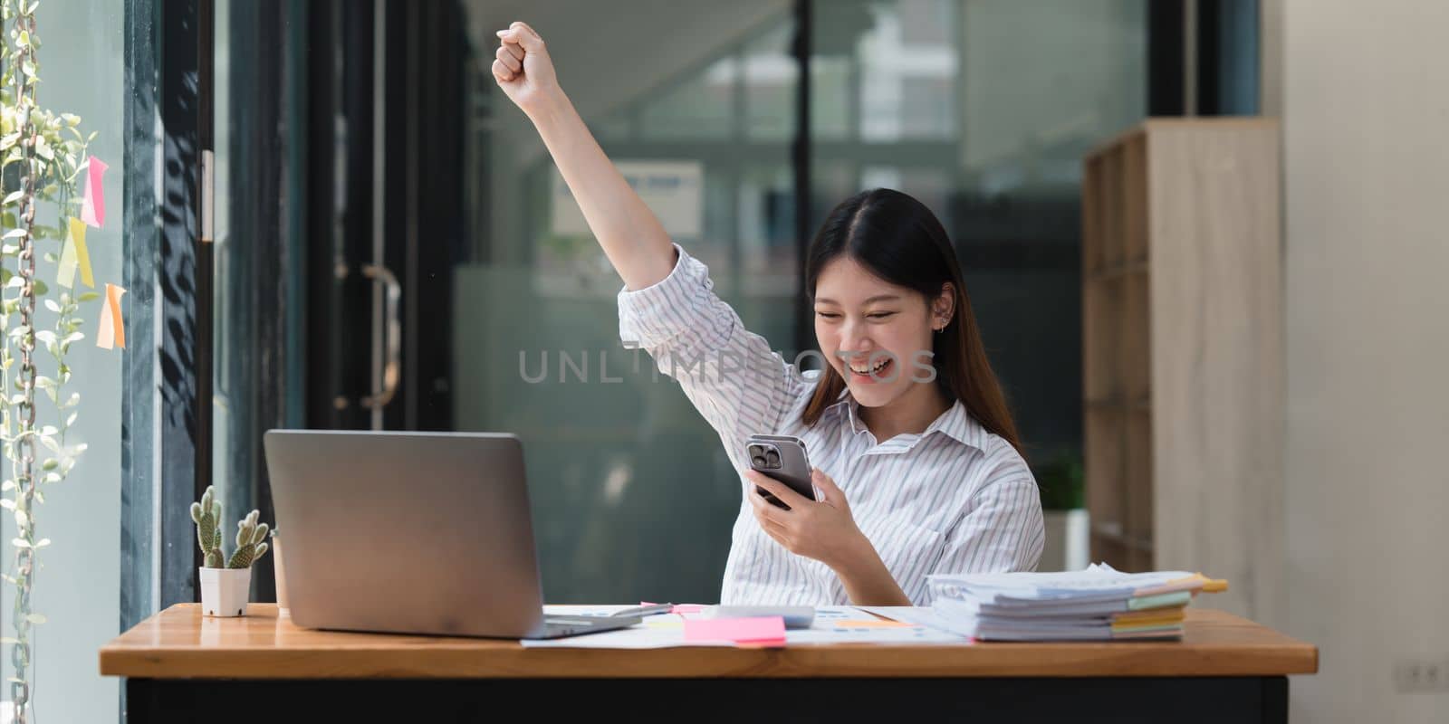 Business people happy to be successful partnership teamwork celebrating achievement and success concept. Beautiful business woman celebrate with cell phone.