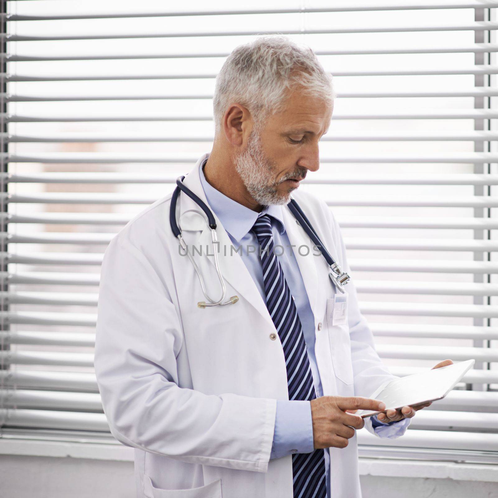 Technology is vital for advancing healthcare. a mature male doctor using a digital tablet. by YuriArcurs