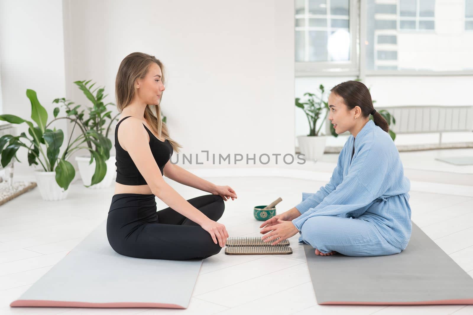 Caucasian and Asian women getting ready to stand on sadhu boards