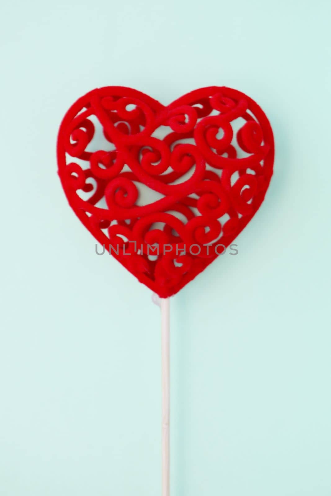 Decorative red gift heart on a stick on a light blue background. Valentine's Day concept. Copy space.
