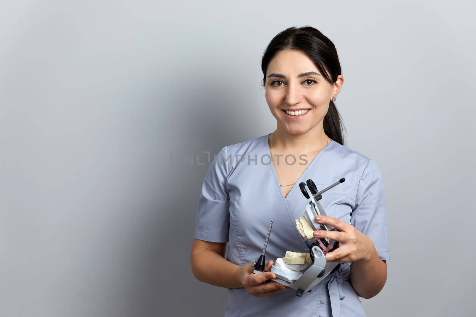 Dentist holding dental articulator with dental gypsum prosthesis model in dental laboratory by Mariakray