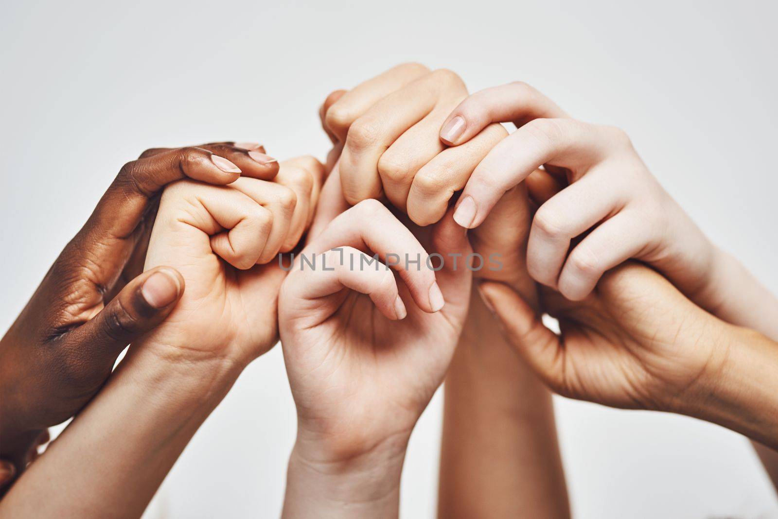 Hold on to whatever makes you stronger. a group of hands holding onto each other against a white background. by YuriArcurs