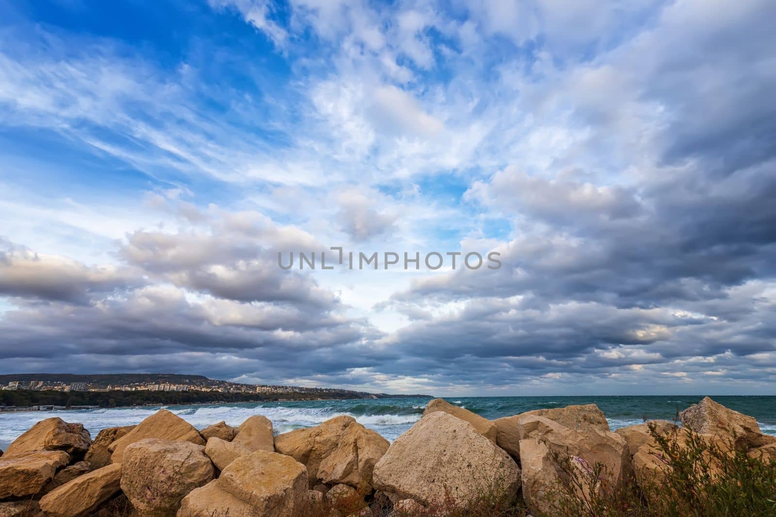 Dramatic clouds over the sea and big rocks at the shore