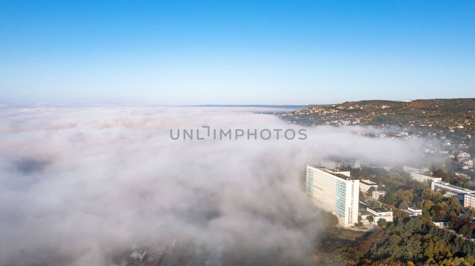 Fog clouds over the city from the sea, view from above