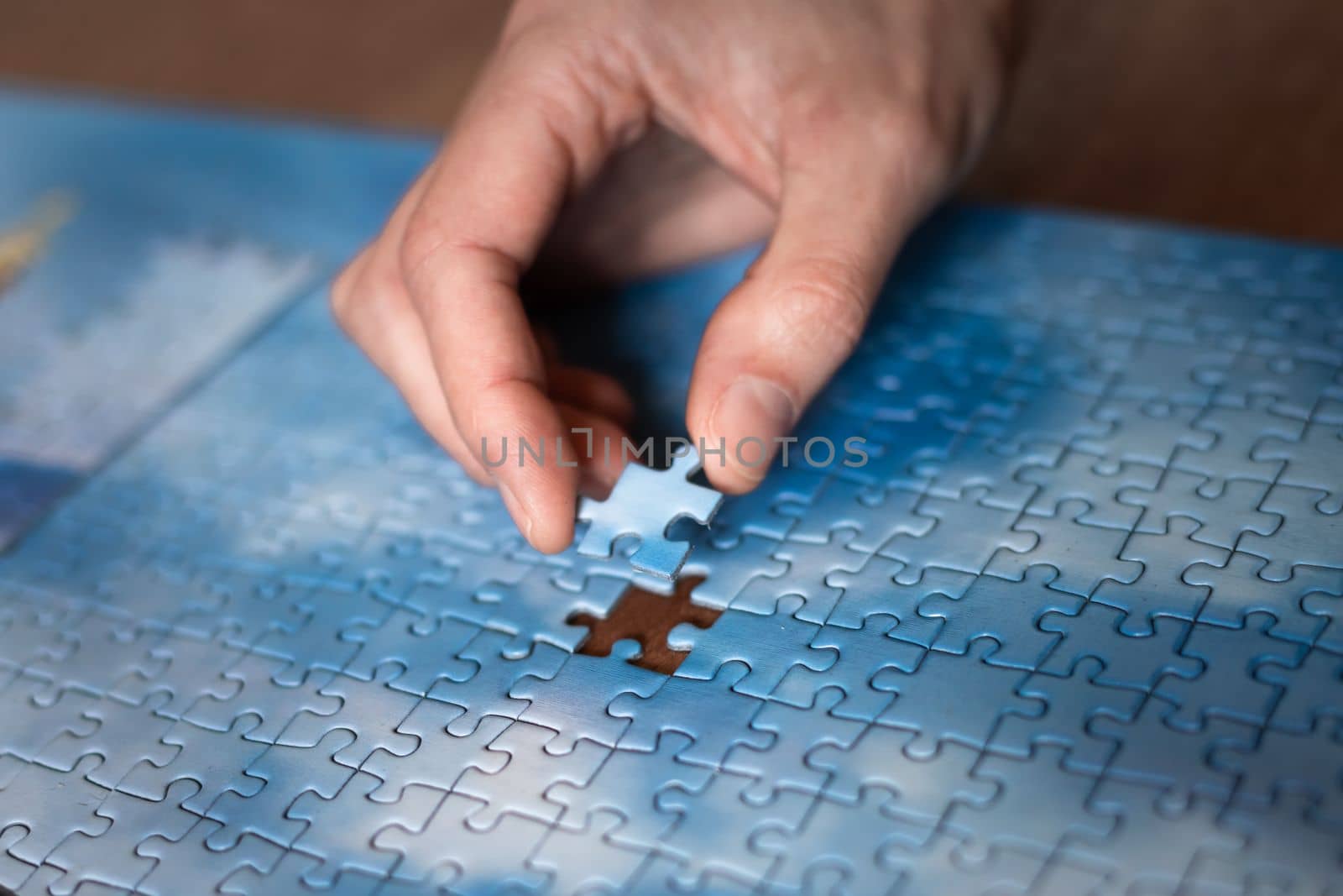 The missing piece of the sky puzzle, the concept of completing a big job, the final of the project, the successful solution of business problems. The hand puts the last piece of the jigsaw