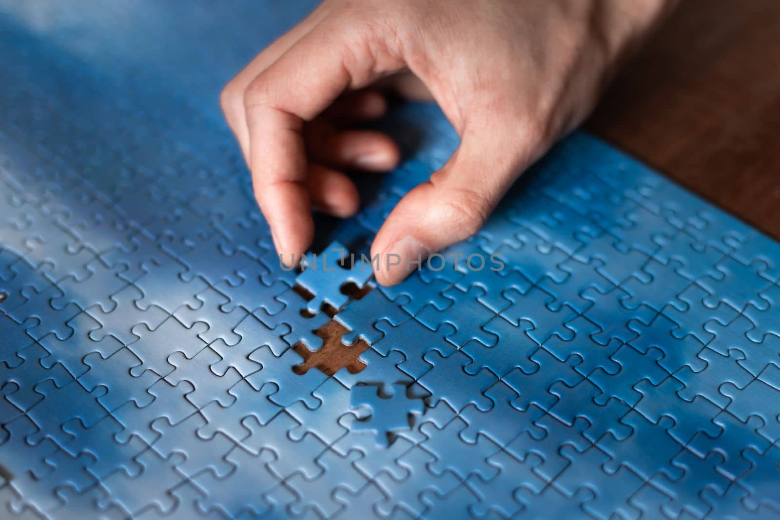 The missing piece of the sky puzzle, the concept of completing a big job, the final of the project, the successful solution of business problems. The hand puts the last piece of the jigsaw