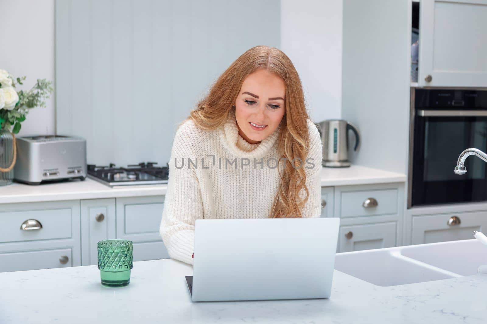 Remote Work. Beautiful middle age Freelancer Lady Working With Laptop In Kitchen, Happy Woman Using Computer At Home, Sitting At Table In Cozy Interior, Enjoying Online Job, Free Space