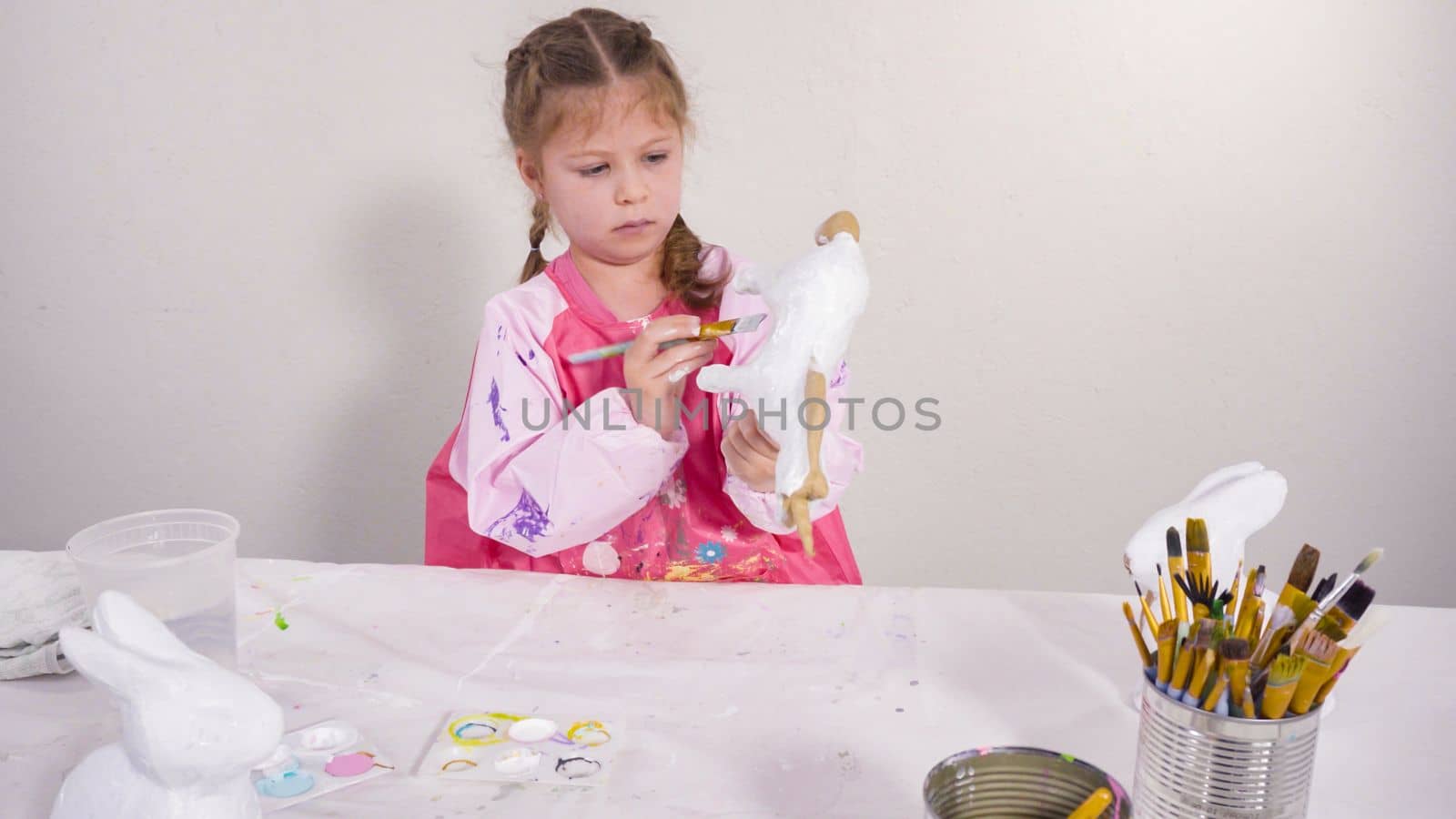 Little girl painting paper mache figurine at homeschooling art class.