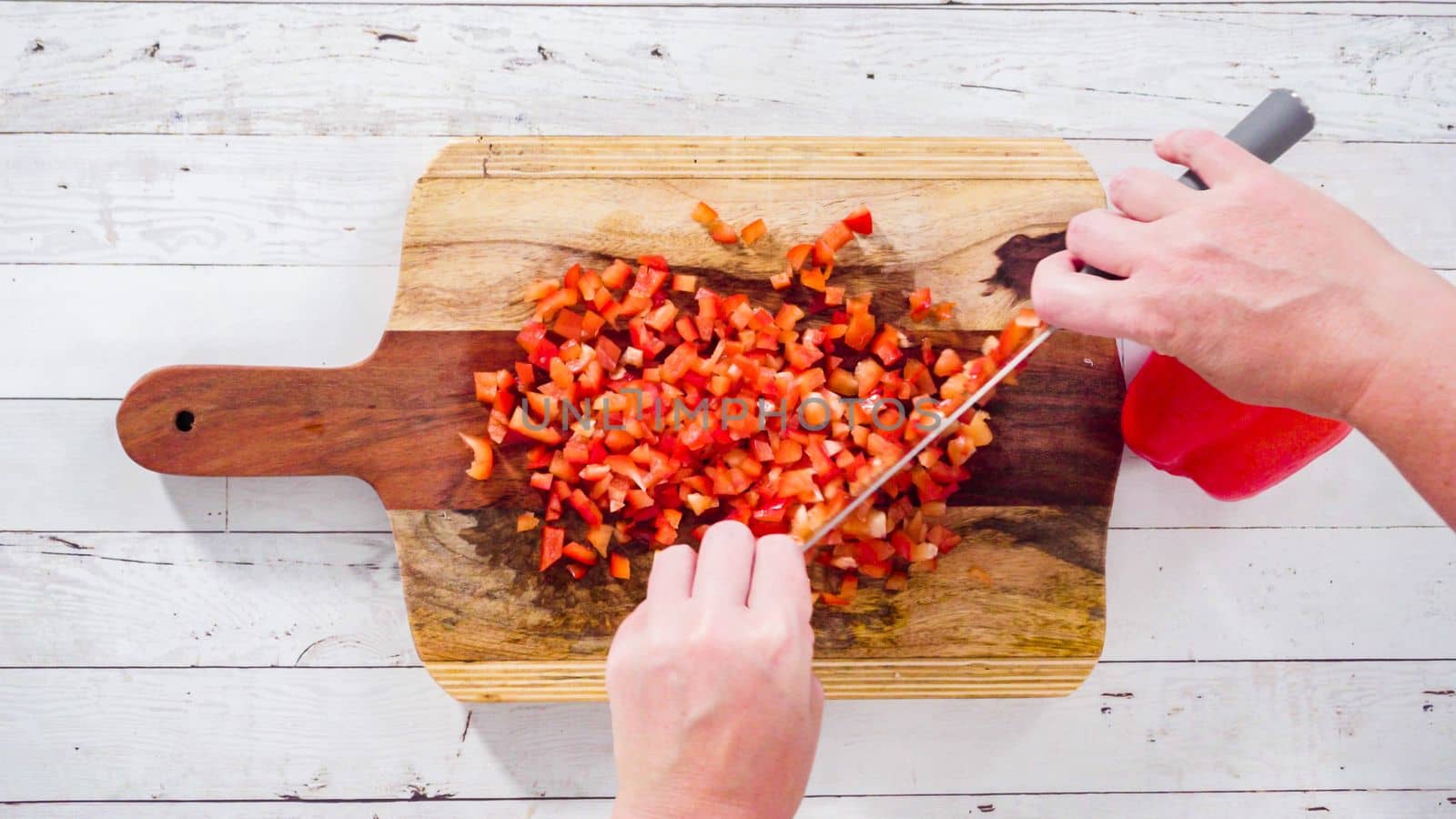Flat lay. Mincing organic red bell peppers on a wood cutting board.