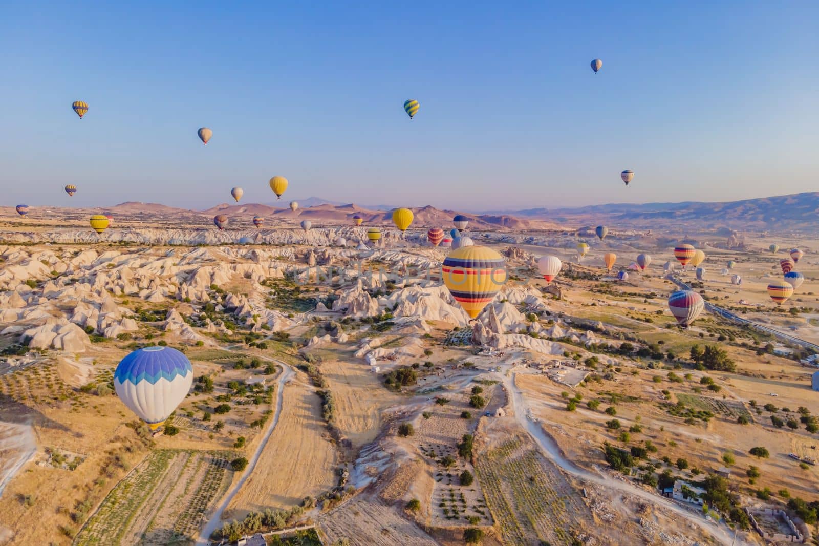 Colorful hot air balloons flying over at fairy chimneys valley in Nevsehir, Goreme, Cappadocia Turkey. Spectacular panoramic drone view of the underground city and ballooning tourism. High quality by galitskaya