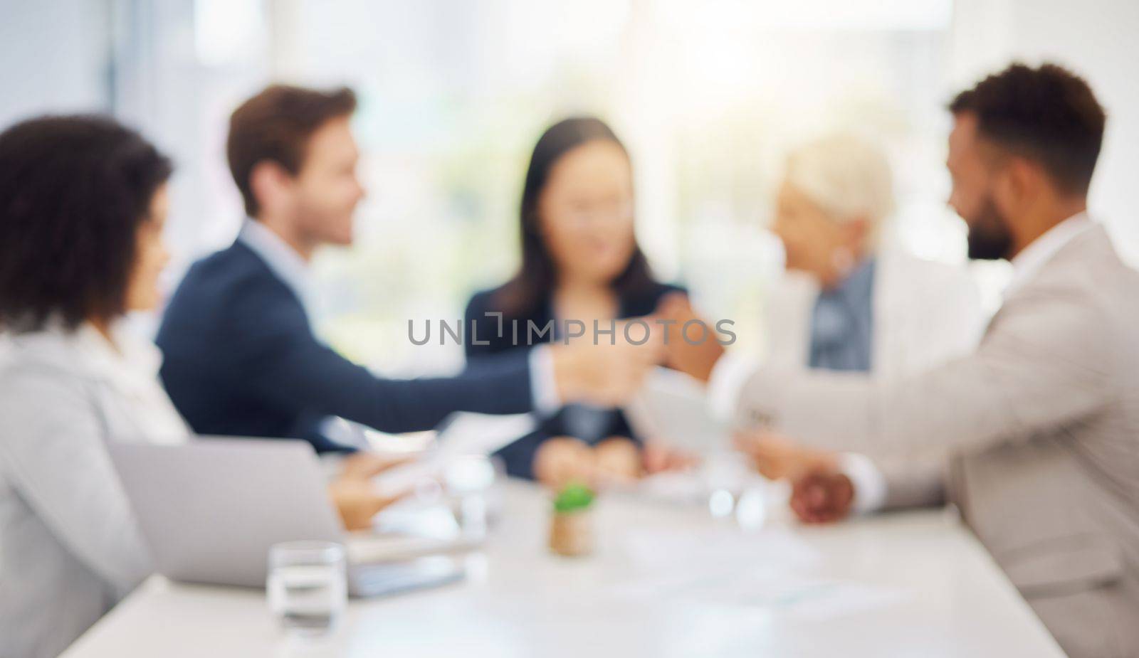 Defocused shot of a group of diverse businesspeople having a meeting in an office boardroom. Blurred shot of colleagues discussing plans and strategies together by YuriArcurs