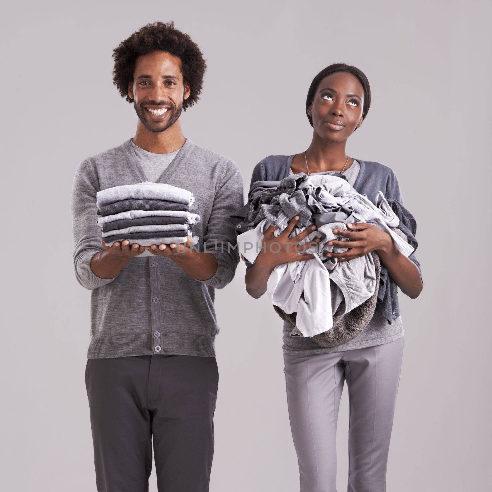 First timers luck. Studio shot of a man holding a neatly folded pile of clothes while his partners is in a mess