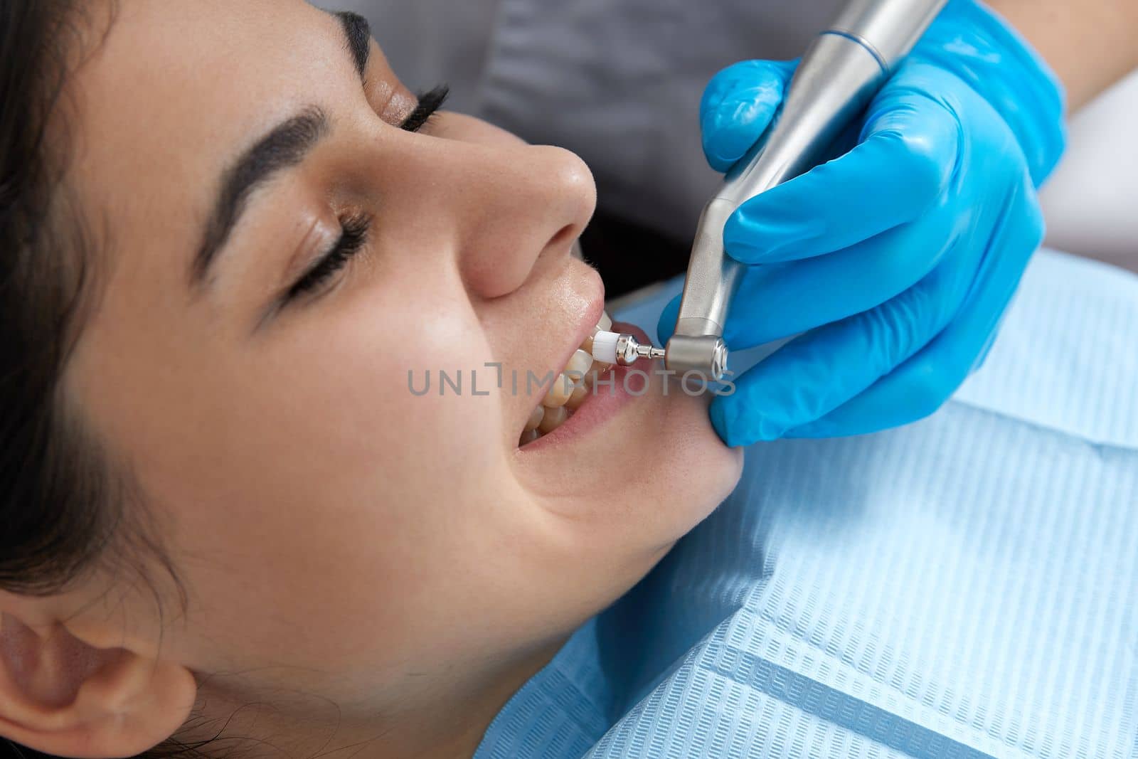 Young woman getting her teeth polished in dental clinic. Professional dental cleaning concept by Mariakray