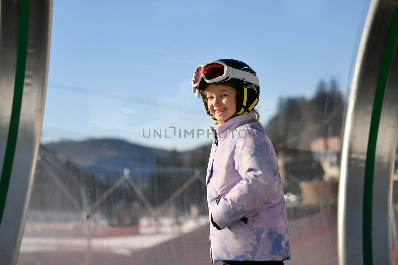 A girl on skis stands on a carpet ski lift in a tunel