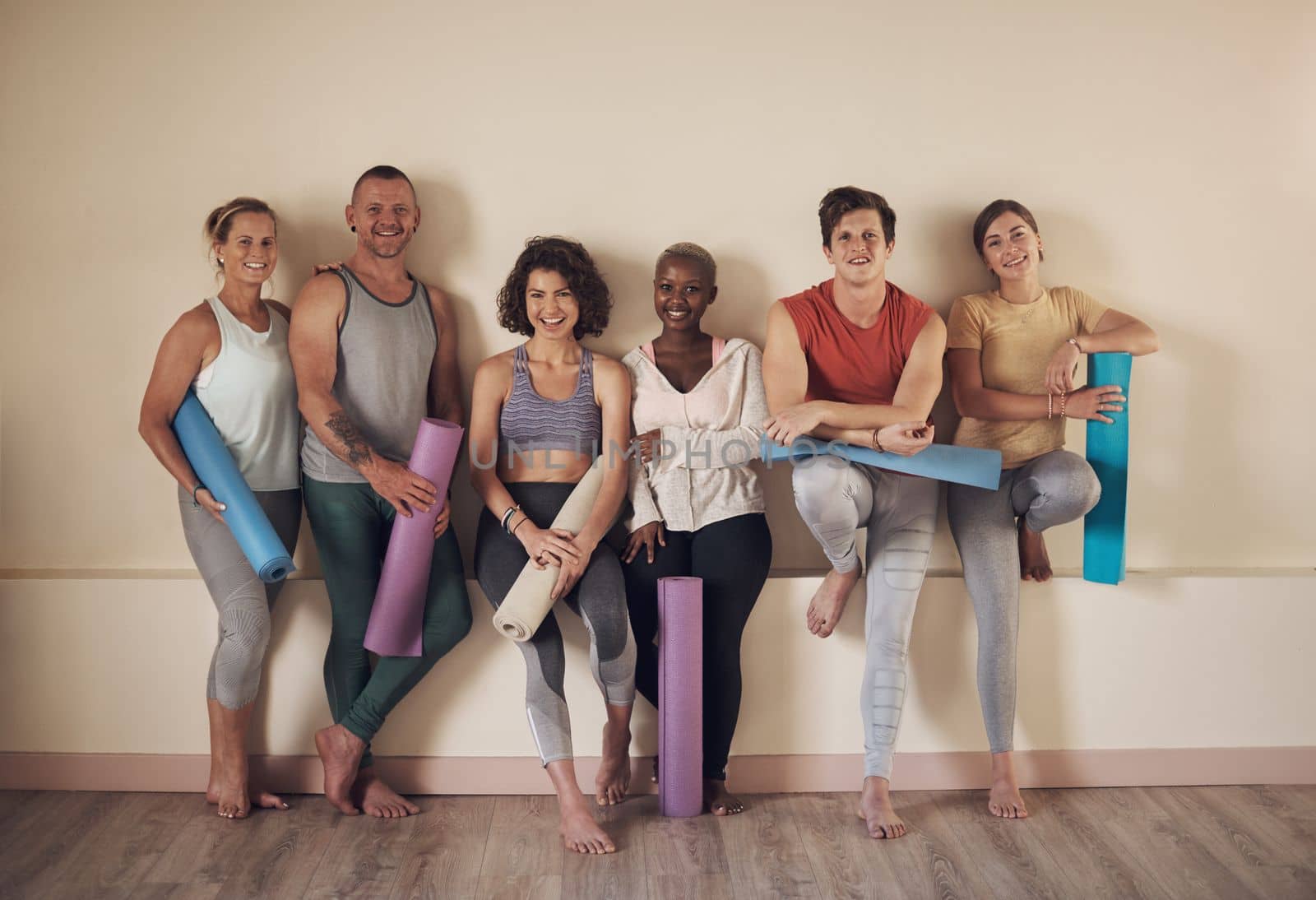 What a great yoga class. Full length portrait of a diverse group of yogis sitting together and bonding after an indoor yoga session