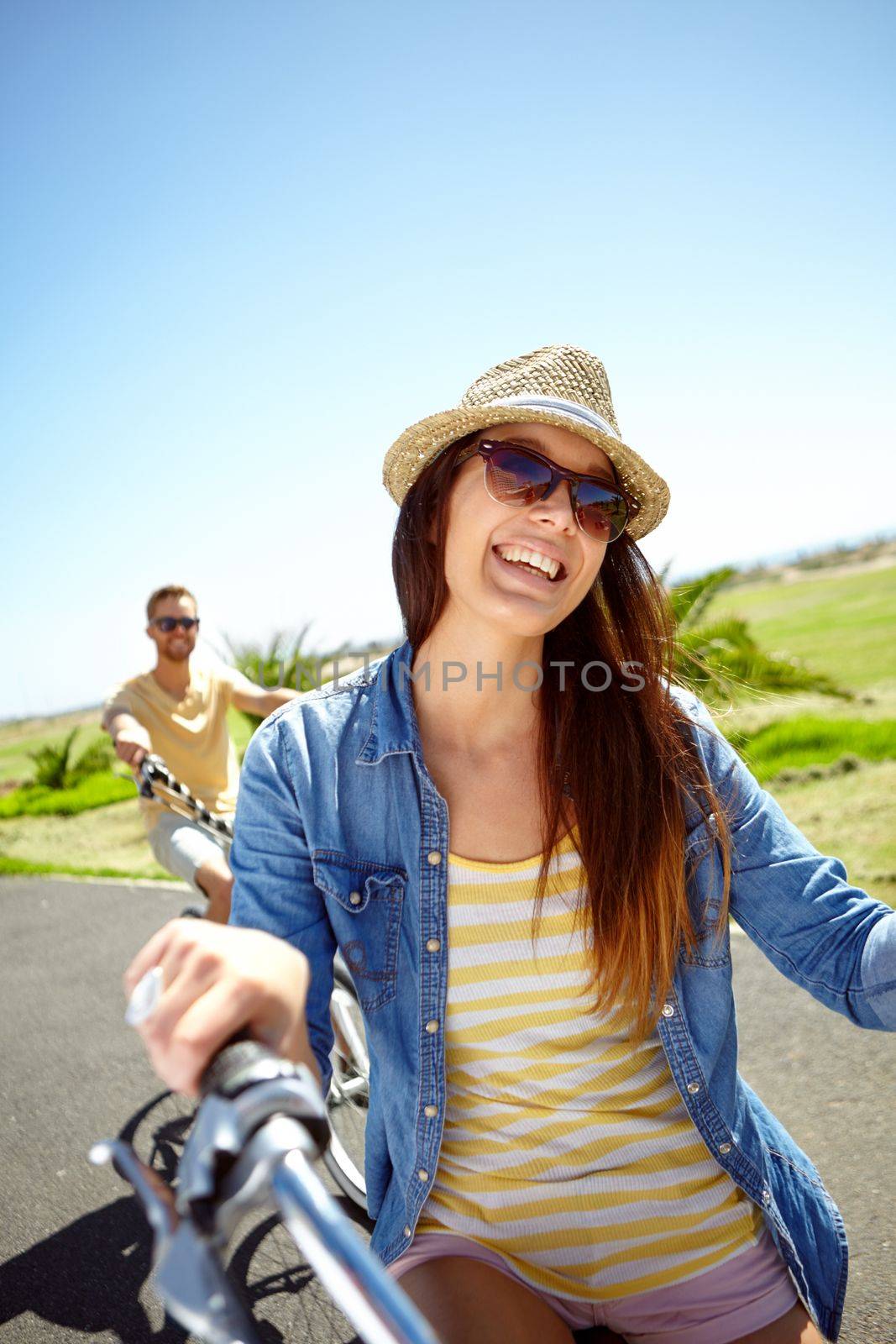 Cycling, travel and woman on couple vacation, summer holiday fun outdoor riding on blue sky background. Bicycle, smile and happy date with partner on bike ride, freedom and happiness with love in sun by YuriArcurs