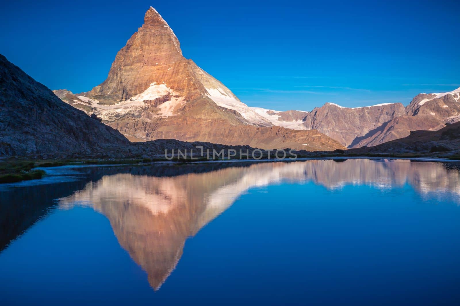 Reflection of the Matterhorn on blue and placid lake at sunrise, Swiss Alps, Zermatt, Switzerland