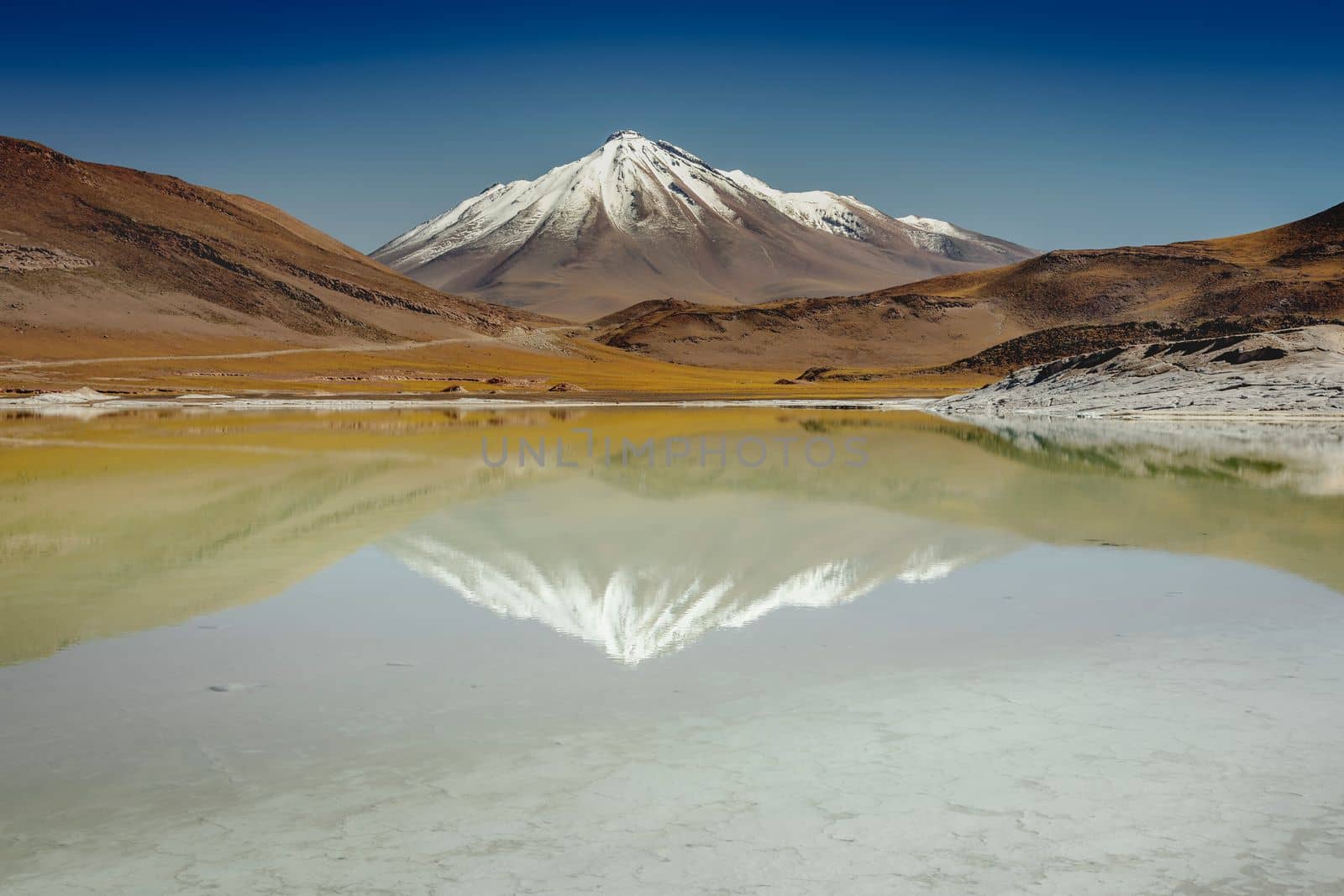 Salt lake reflection and idyllic volcanic landscape at sunrise, Atacama desert, Chile border with Bolivia