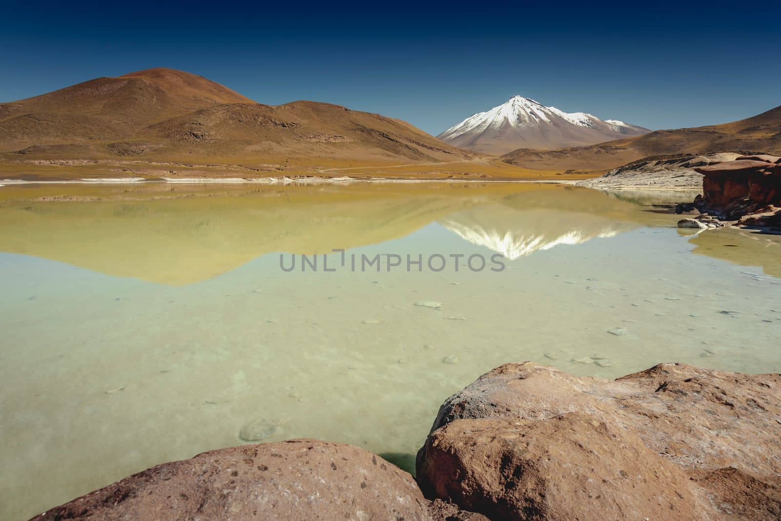 Salt lake reflection and idyllic volcanic landscape at sunrise, Atacama desert, Chile border with Bolivia